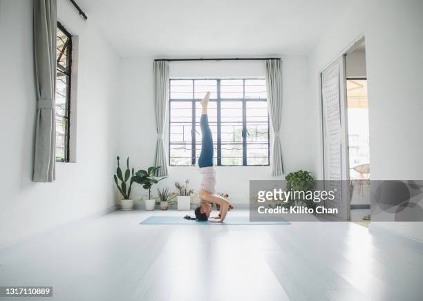asian woman practicing yoga in a yoga studio-head stand pose - salle yoga photos et images de collection