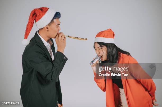 asian chinese mature couple having fun christmas party horn blower studio shoot with gray background - party horn blower imagens e fotografias de stock