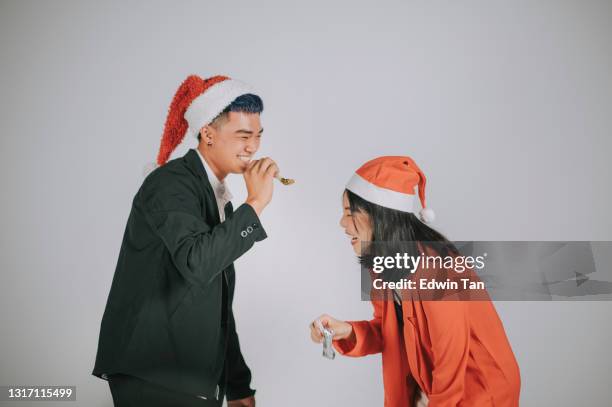 asian chinese mature couple having fun christmas party horn blower studio shoot with gray background - 18 23 months stock pictures, royalty-free photos & images