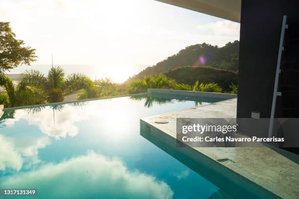 luxury swimming pool next to a building in the middle of the jungle with the sky in reflection - reflection pool - fotografias e filmes do acervo