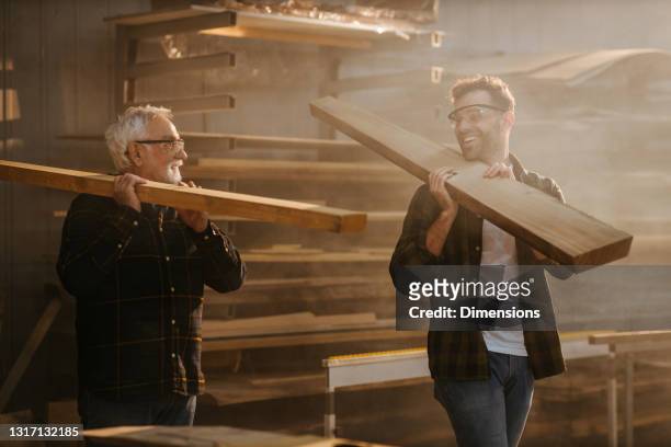 far och son arbetar med en planka i verkstaden - father son business bildbanksfoton och bilder