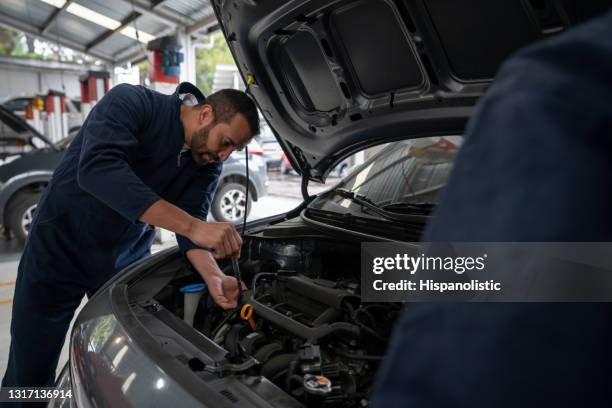meccanico che lavora in un'officina di riparazione automatica per riparare un'auto - car bonnet foto e immagini stock