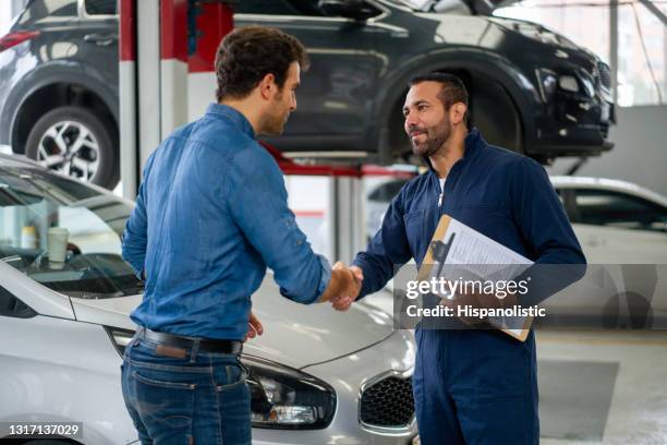 mens die een monteur met een handdruk begroet bij een autoreparatiewerkplaats - car mechanic stockfoto's en -beelden