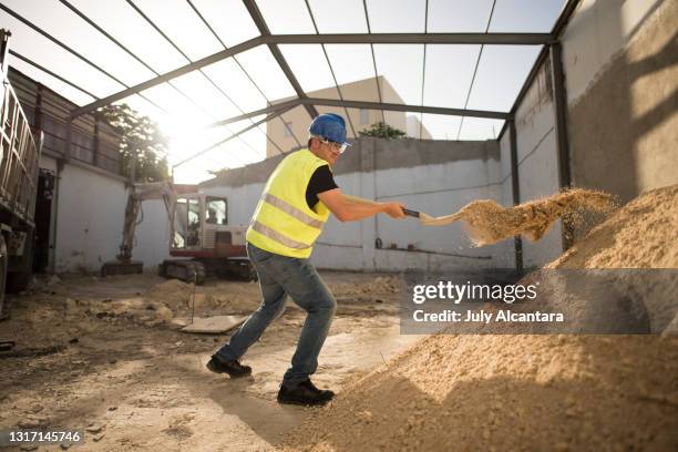 construction worker with a shovel moves the sand so that it is less compact and looser and make the mixture in the concrete mixer - vehicle scoop stock pictures, royalty-free photos & images