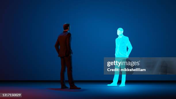 man looks at a digital avatar of himself made with a hologram - avatars imagens e fotografias de stock