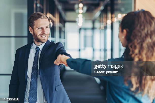 business persons greeting with a fist bump - epidemic suit stock pictures, royalty-free photos & images