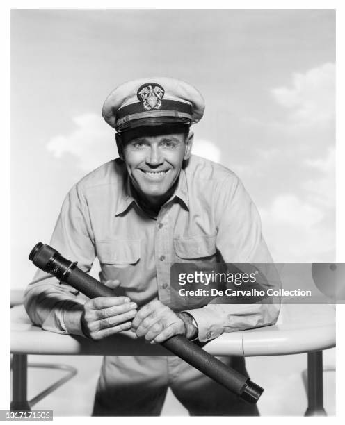Actor Henry Fonda in navy uniform and holding a refracting telescope, as 'Lieutenant jg Douglas A Roberts', in a publicity shot from the movie...