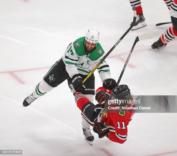 Jamie Benn of the Dallas Stars dumps Adam Gaudette of the Chicago Blackhawks in the first period at the United Center on May 09, 2021 in Chicago,...