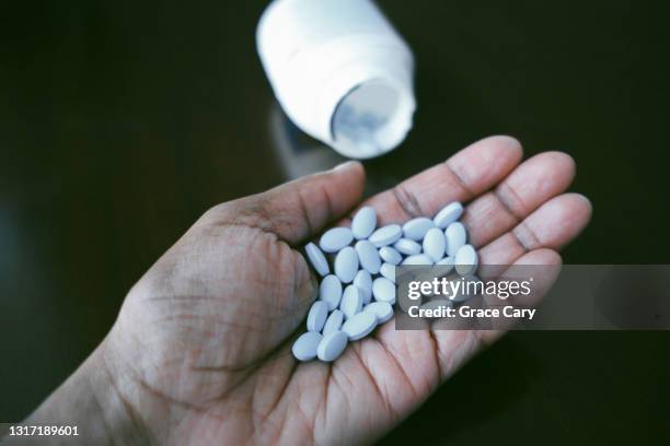 woman holds pills in palm of hand - paracetamol stockfoto's en -beelden