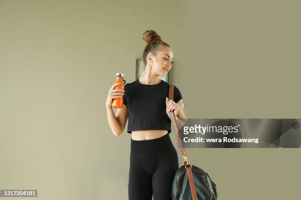 healthy woman wearing exercise clothes carry sports bag and water bottle while walking - gym bag fotografías e imágenes de stock