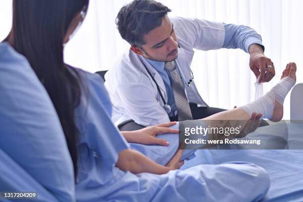 a doctor making a wound dressing leg young lady patient - leg wound stockfoto's en -beelden