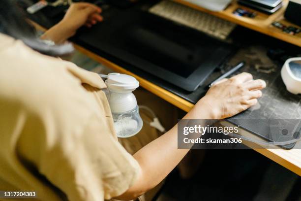 asian newbie mother pumping expressing breast milk pumping equipment at home - trying stockfoto's en -beelden