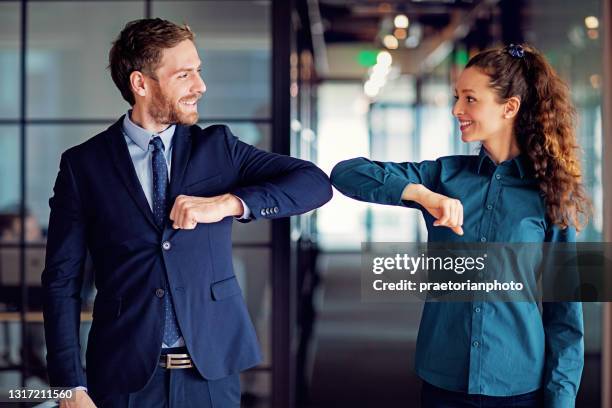 empresarios haciendo saludos con golpe de codo durante la pandemia covid-19 - elbow bump fotografías e imágenes de stock