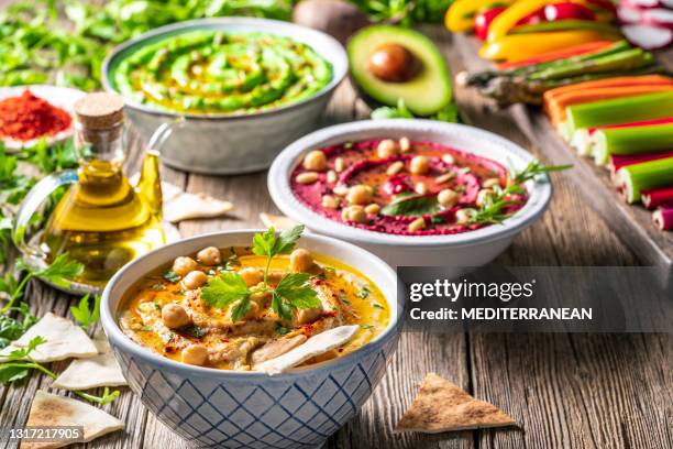 hummus three bowl of chickpeas, avocado and beetroot vegetables for dip on rustic wooden table - lebanon country stock pictures, royalty-free photos & images