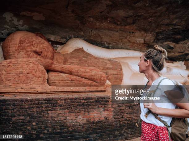 giovane donna contempla statua buddha in roccia - sigiriya foto e immagini stock