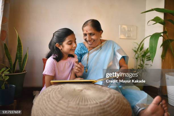 grandmother reading story book to her granddaughter - storyteller 個照片及圖片檔