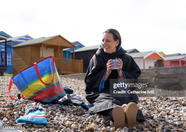 woman keeping warm on the beach - menopossibilities stock-fotos und bilder