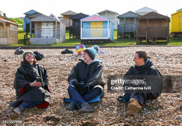 group of friends sit and laugh on the beach - menopossibilities stock pictures, royalty-free photos & images