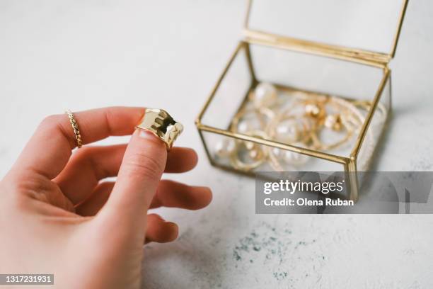 a woman's hand holds a gold ring - jewellery display stock pictures, royalty-free photos & images