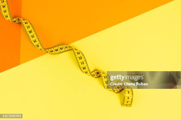 yellow measuring tape on a bright orange-yellow background - mètre à ruban photos et images de collection