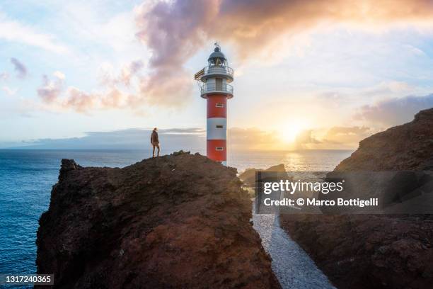 tourist admiring sunset at teno lighthouse, tenerife, spain. - travel guidance stock pictures, royalty-free photos & images