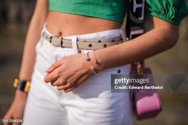 Amanda Derhy @amanda_jashley wears a green cropped top from Zara, a pink Furla bag, a beige leather Longchamp belt, white flared denim pants, a...