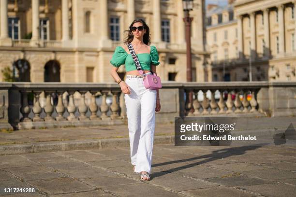 Amanda Derhy @amanda_jashley wears sunglasses, a green low-neck straight neck cropped top with puff shoulders from Zara, a pink Furla bag, a beige...