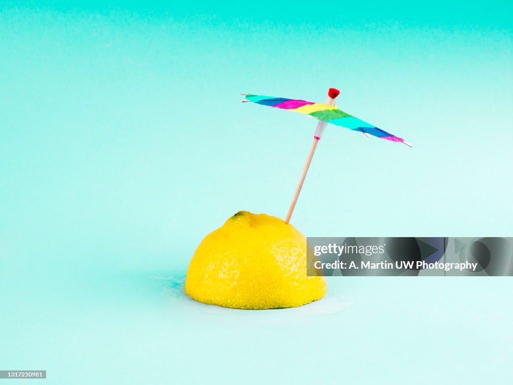Tropical beach concept made of lemon and sun umbrella.