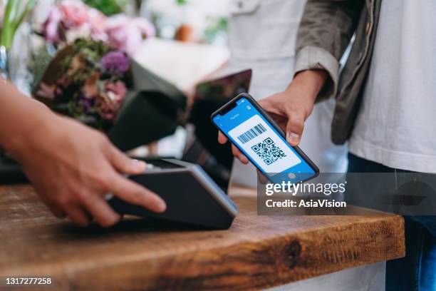 gelukkig paar dat bij de bloemenwinkel winkelt. sluit omhoog van jonge aziatische mens die voor een boeket betaalt door qr-code te scannen, te scannen en een rekening op een kaartmachine te betalen die een snelle en gemakkelijke contactloze betaling maakt. - qr stockfoto's en -beelden