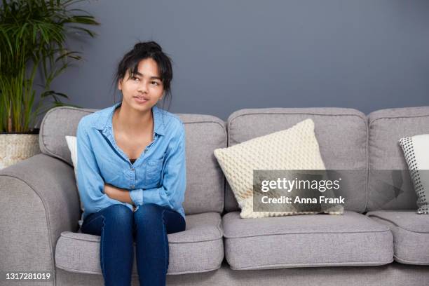 teenage girl sitting on the sofa in pain - only teenage girls stock pictures, royalty-free photos & images