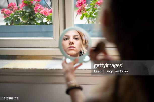 beautiful young woman seen via a hand mirror, putting on make-up - handspiegel stock-fotos und bilder