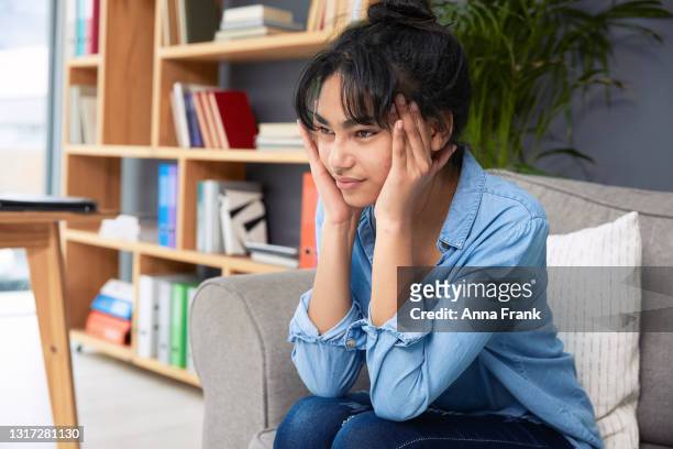 teenager-mädchen sitzt auf dem sofa mit kopfschmerzen - asian massage girl stock-fotos und bilder