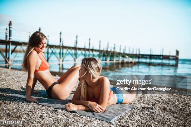 beautiful females sunbathing at beach - beach bum imagens e fotografias de stock