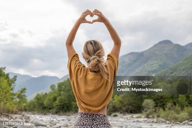 young woman loving nature, she makes heart with hands - heart hands stock pictures, royalty-free photos & images