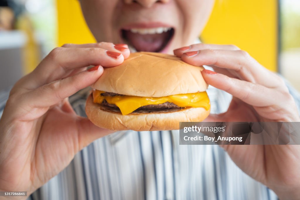 Close up of woman opened her mouth to eat a cheese burger.