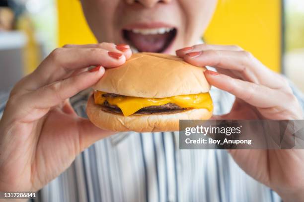 close up of woman opened her mouth to eat a cheese burger. - cheesburguer - fotografias e filmes do acervo