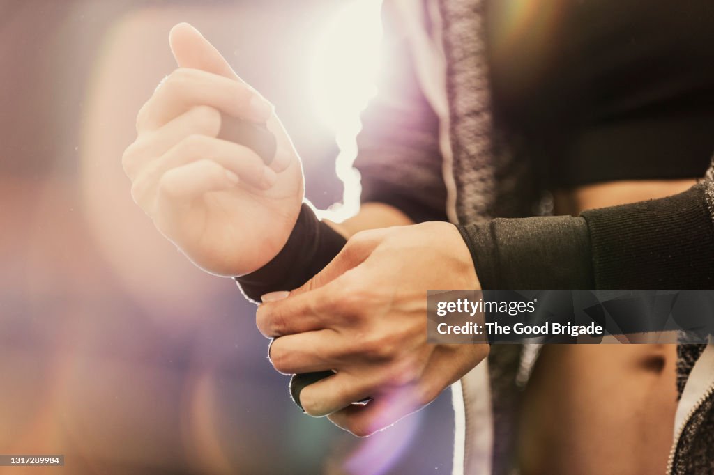 Midsection of woman adjusting wrist wraps at gym