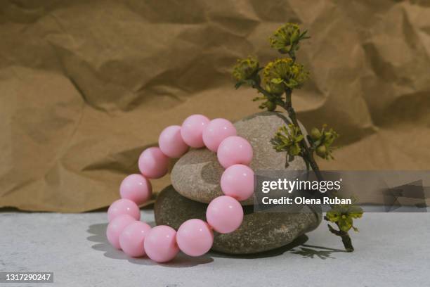a pink bracelet with round beads lies on sea stones - bracelet stock pictures, royalty-free photos & images