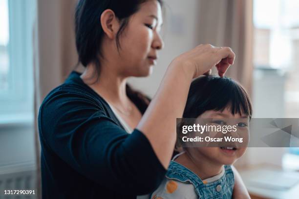 asian mother assisting her little daughter to tidy up her hair - brushing hair stock pictures, royalty-free photos & images