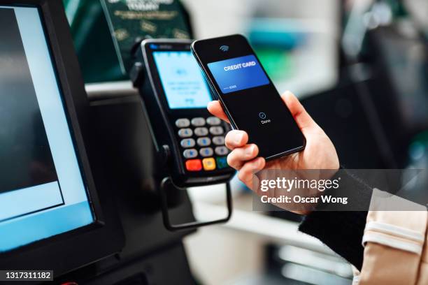 close-up shot of a woman using contactless payment via smartphone to pay for her shopping at self-checkout counter in a store - close up counter stock pictures, royalty-free photos & images