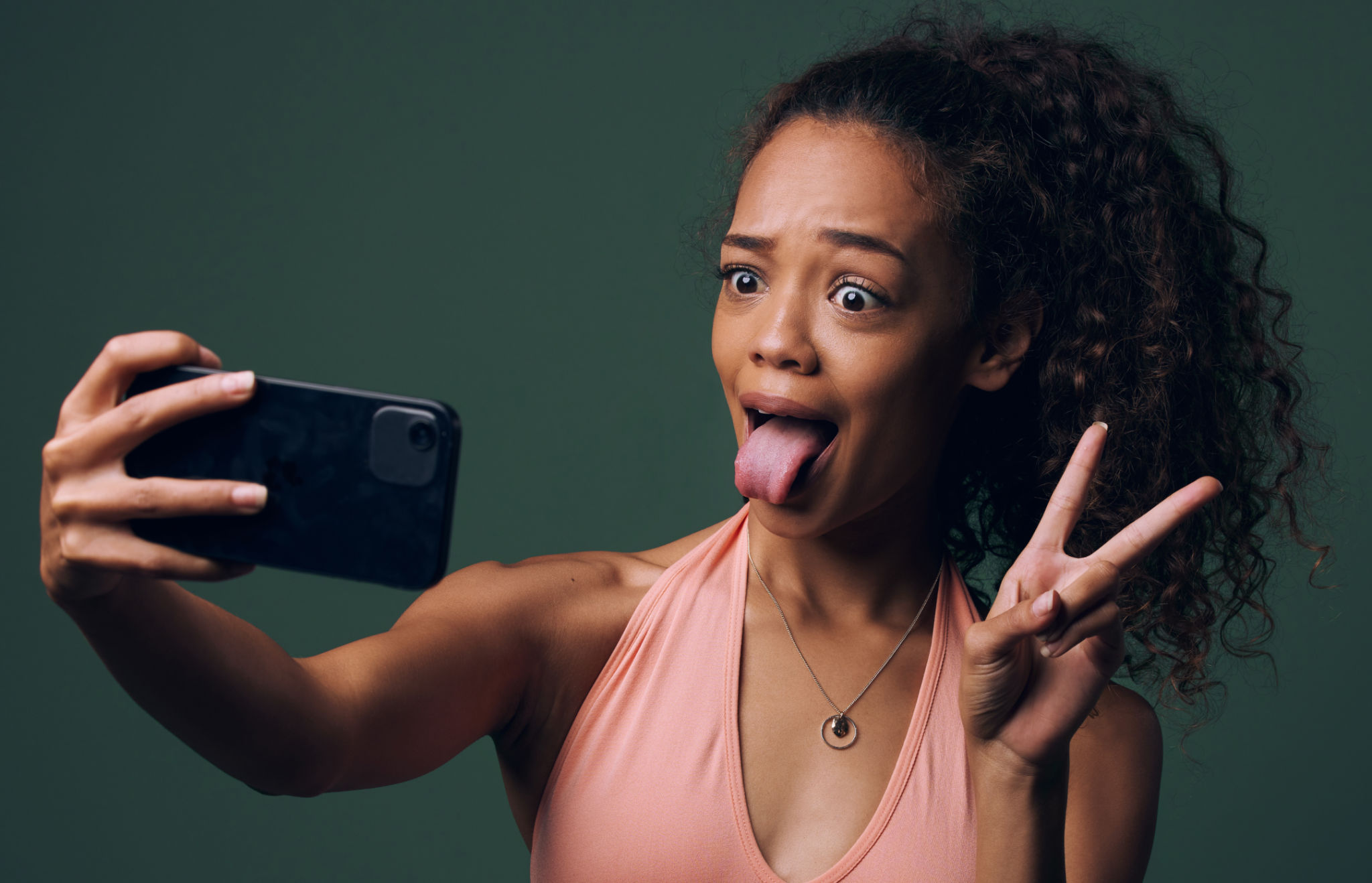 Cropped shot of an attractive and quirky young woman posing against a green background in studio Cropped shot of an attractive and quirky young woman posing against a green background in studio