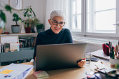 Smiling Senior Businesswoman Sitting in her Office and Working on her Laptop