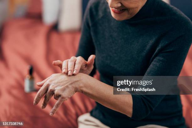 hand skincare: mulher sênior anônima aplicando creme para as mãos - dry skin - fotografias e filmes do acervo