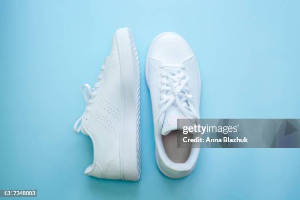 white sports shoes over blue background, sports and casual clothing style concept. summer or spring fashion. - blaue schuhe stock-fotos und bilder