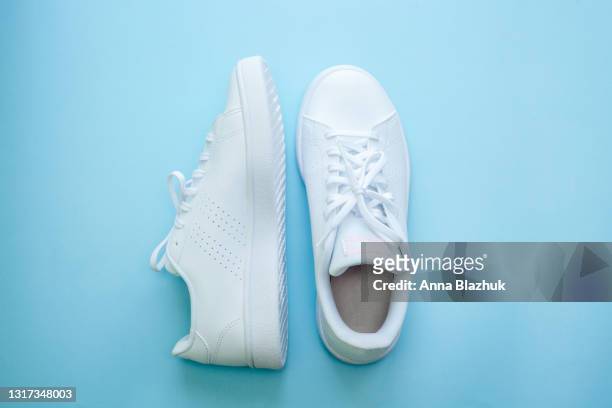 white sports shoes over blue background, sports and casual clothing style concept. summer or spring fashion. - footwear photos et images de collection