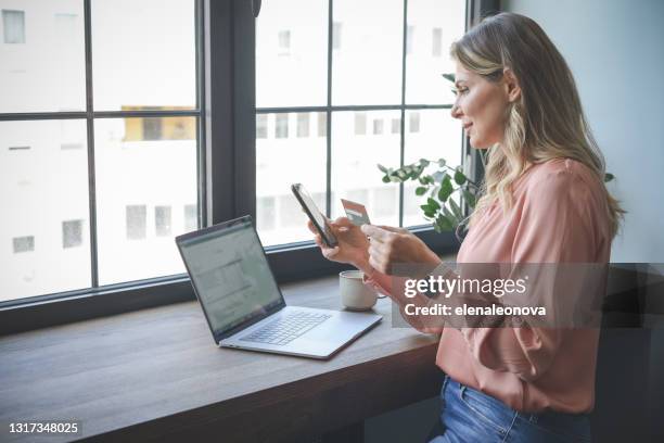 有吸引力的中年婦女在辦公室工作（網上購物智能手機） - window sill 個照片及圖片檔
