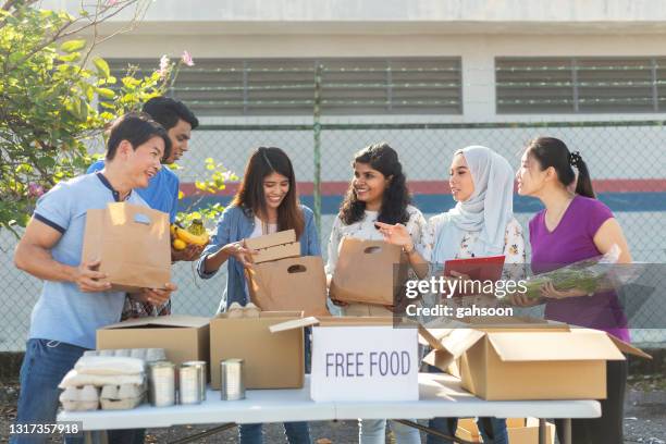 glückliche multiethnische freiwillige bei food bank bereiten sich auf wohltätige lebensmittel-antrieb - großzügigkeit stock-fotos und bilder