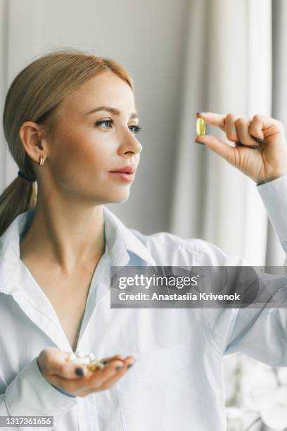 beautiful female doctor looks at the pill. - hand holding several pills photos et images de collection