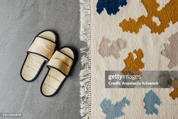 natural straw eco slippers and multicoloured carpet. - dekorativ matta bildbanksfoton och bilder