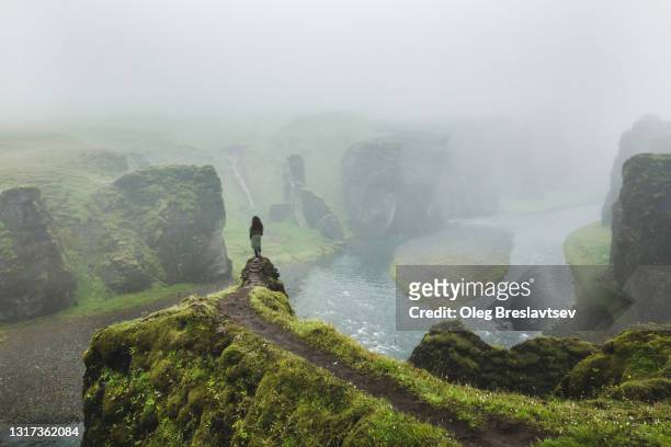 woman hiking in fjadrargljufur canyon in iceland in cloudy foggy weather. mystical atmosphere - wilderness stock pictures, royalty-free photos & images